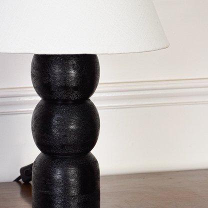 Table lamp closeup showing textured fabric shade and rounded black base details with soft illumination highlighting craftsmanship and elegant modern finish.