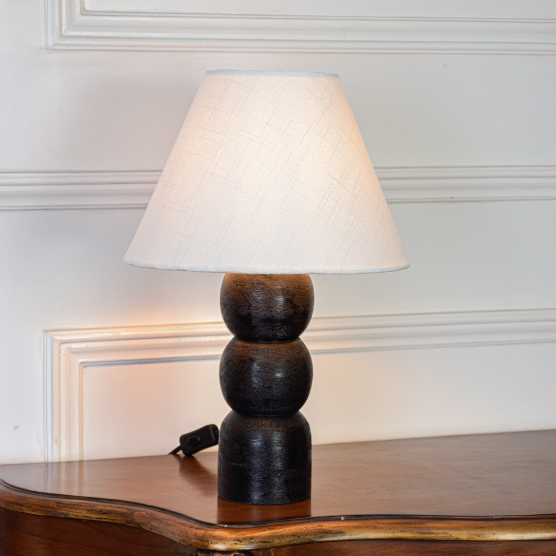 Table lamp shown on clean white background with fabric shade turned on highlighting smooth black base stacked design and modern home lighting appeal.
