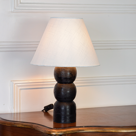 Table lamp shown on clean white background with fabric shade turned on highlighting smooth black base stacked design and modern home lighting appeal.