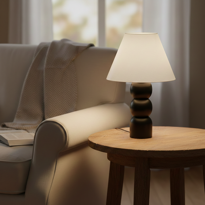 Table lamp styled beside a cozy sofa on a wooden side table with soft warm glow creating a calm living room mood with natural light accents.