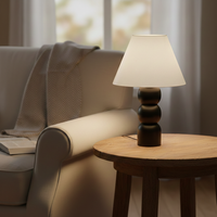 Table lamp styled beside a cozy sofa on a wooden side table with soft warm glow creating a calm living room mood with natural light accents.