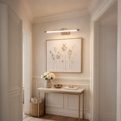 Gold metal picture light accentuating framed artwork above console table bringing gallery style elegance to interior spaces.