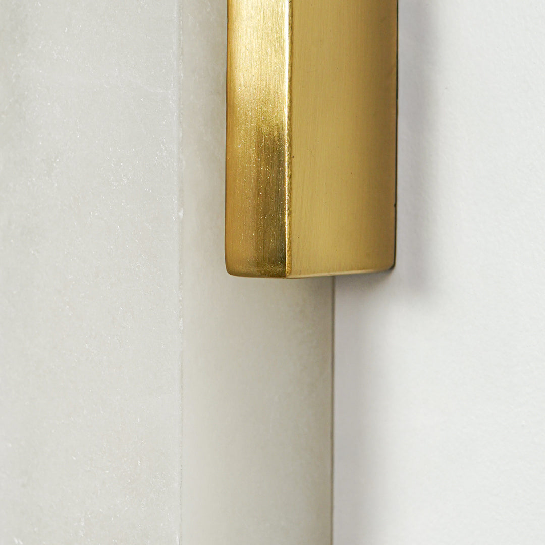 Close view of gold metal wall sconce with cylindrical frosted glass shade showcasing premium modern lighting design on clean background.
