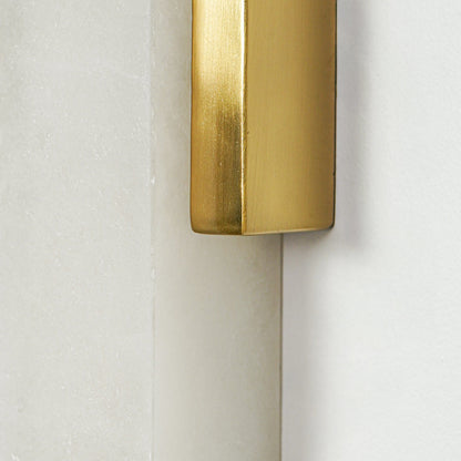 Close view of gold metal wall sconce with cylindrical frosted glass shade showcasing premium modern lighting design on clean background.