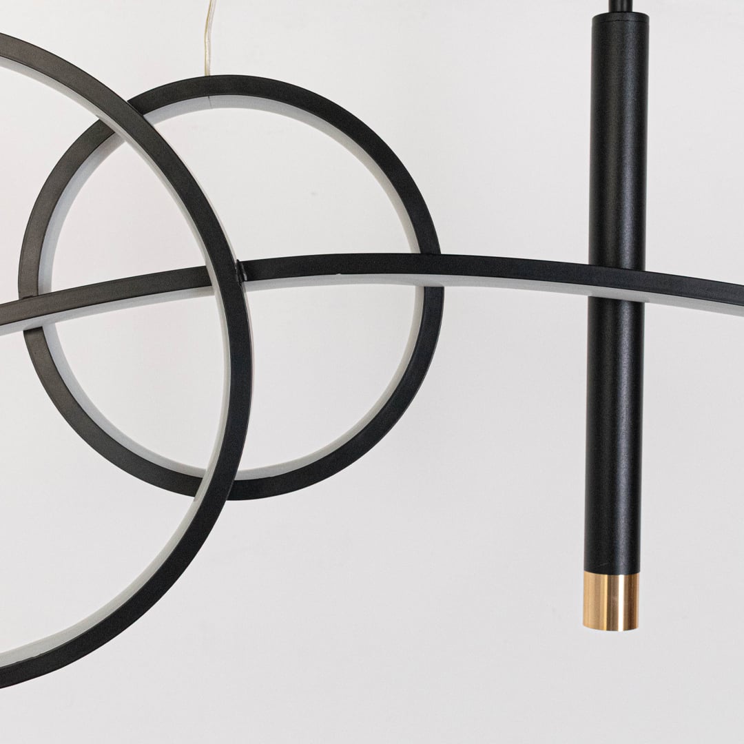 Closeup of pendant light with golden glow circular rings and slim black frame for stylish ceiling lighting design.