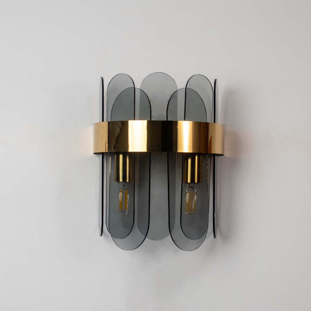 A metal and smoked glass wall light with bulbs off displayed on a white background showcasing the elegant layered glass design for home interiors.