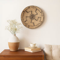 Decorative wall basket styled above console table with ceramic vase books and plant creating cozy modern living room Decor.
