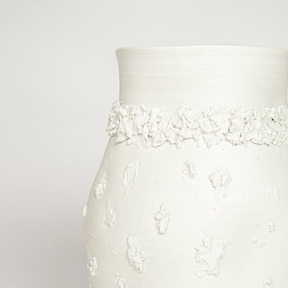 Closeup of white glazed ceramic vase with intricate raised detailing ideal for elegant home decor shelf or side table styling.