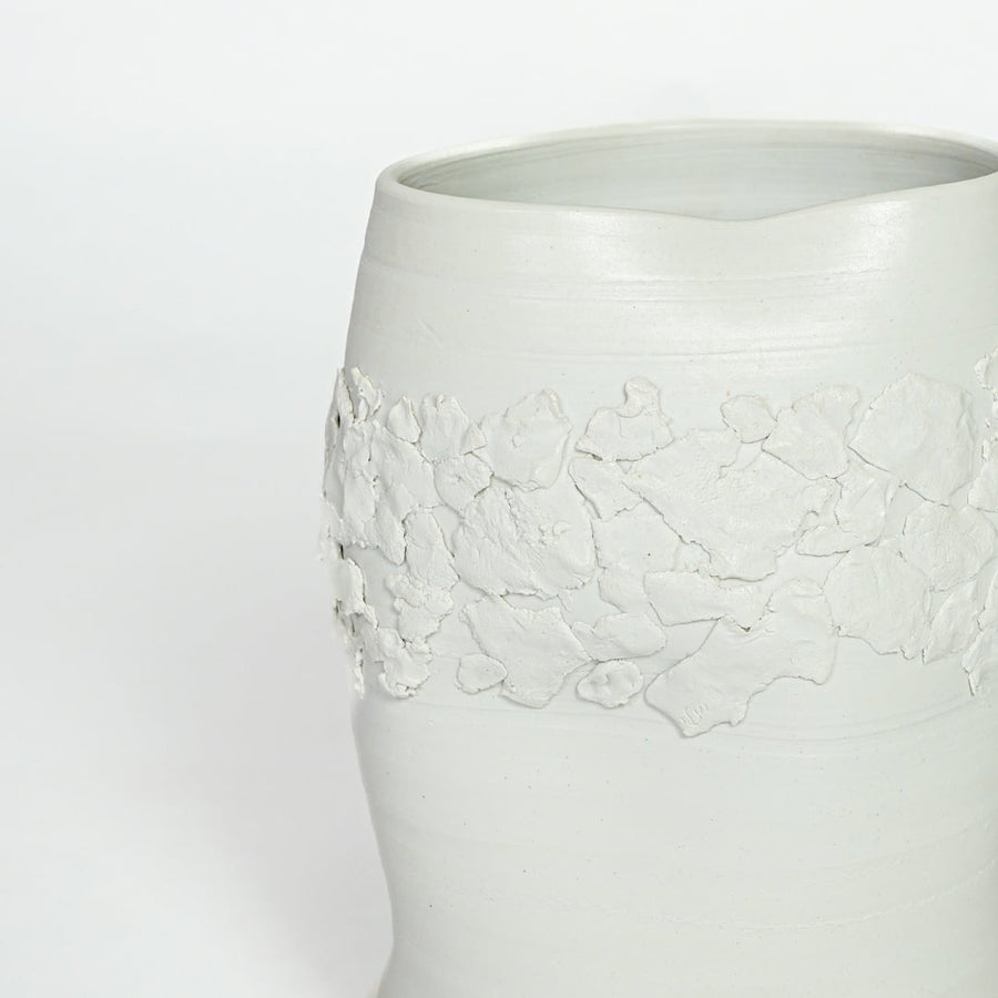 Detailed closeup of white ceramic vase showcasing embossed floral band and refined matte finish.