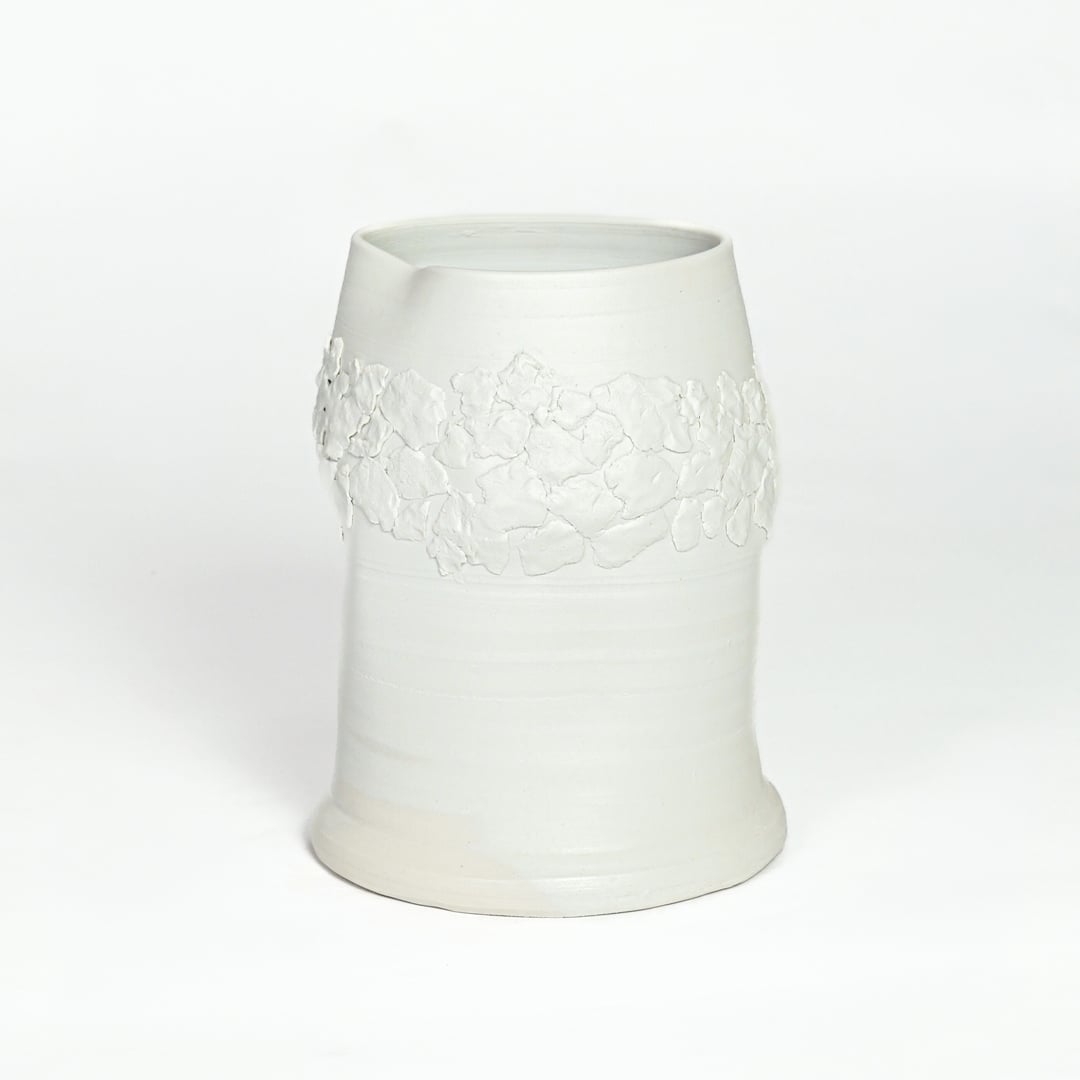 White ceramic decorative vase with embossed floral band isolated on white background for elegant tabletop decor placement.