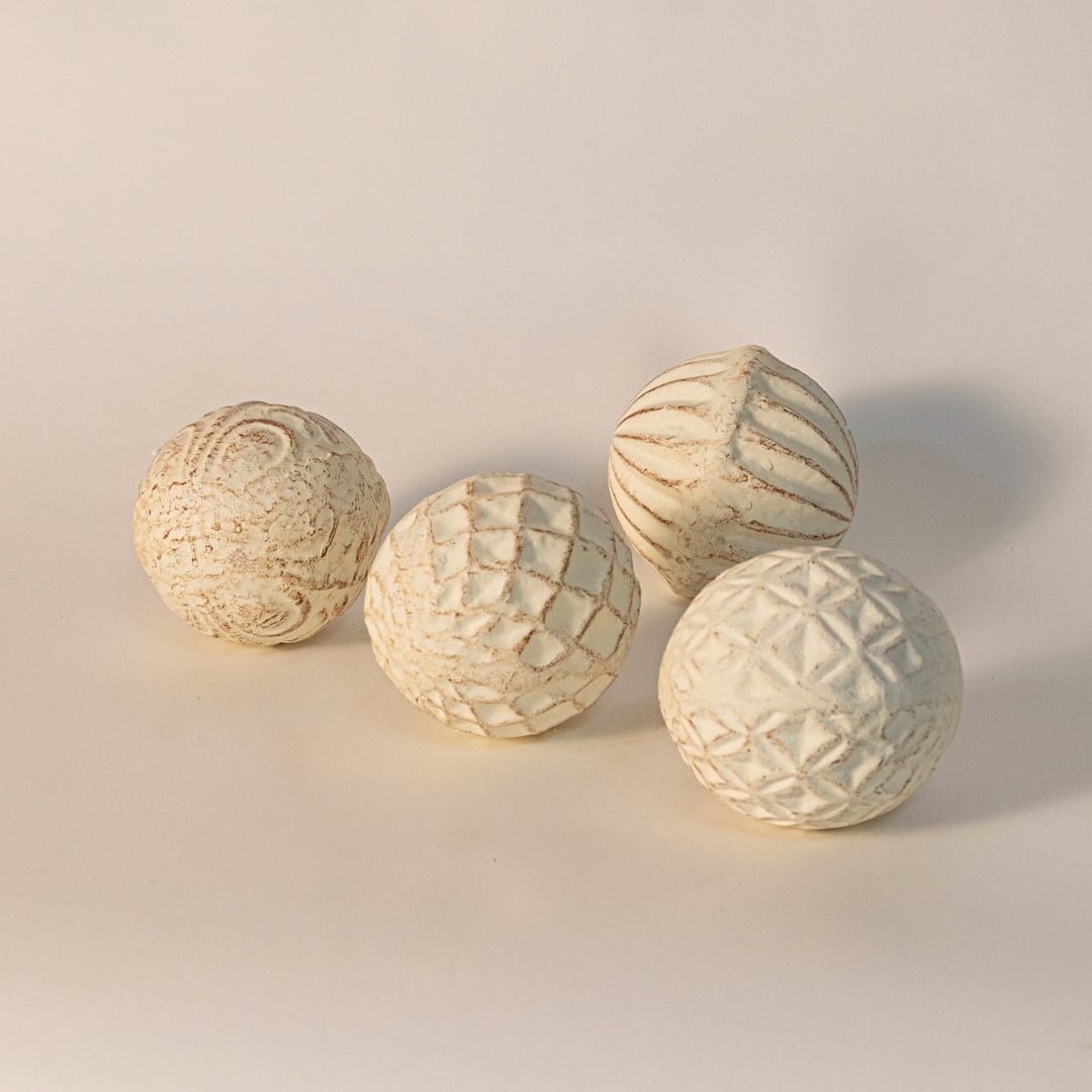 Handcrafted ceramic ball with carved geometric texture displayed on white background highlighting artisanal detail.