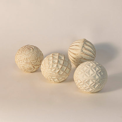 Handcrafted ceramic ball with carved geometric texture displayed on white background highlighting artisanal detail.