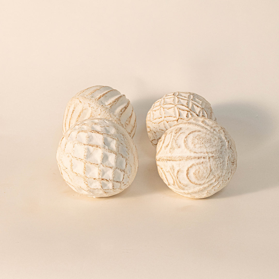 Decorative textured spheres in off white finish with carved patterns for table decor or shelf styling modern home placement white background.