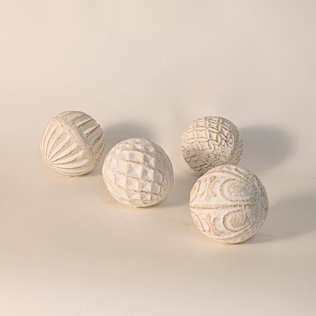 Decorative carved ball on plain white background showcasing handmade surface texture and organic spherical shape.