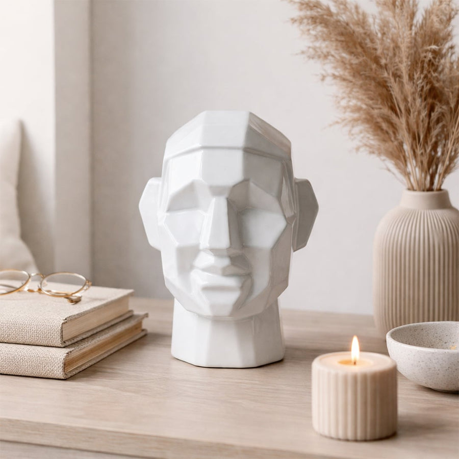 White ceramic decorative face sculpture styled beside dried pampas grass for modern shelf styling and home decor.