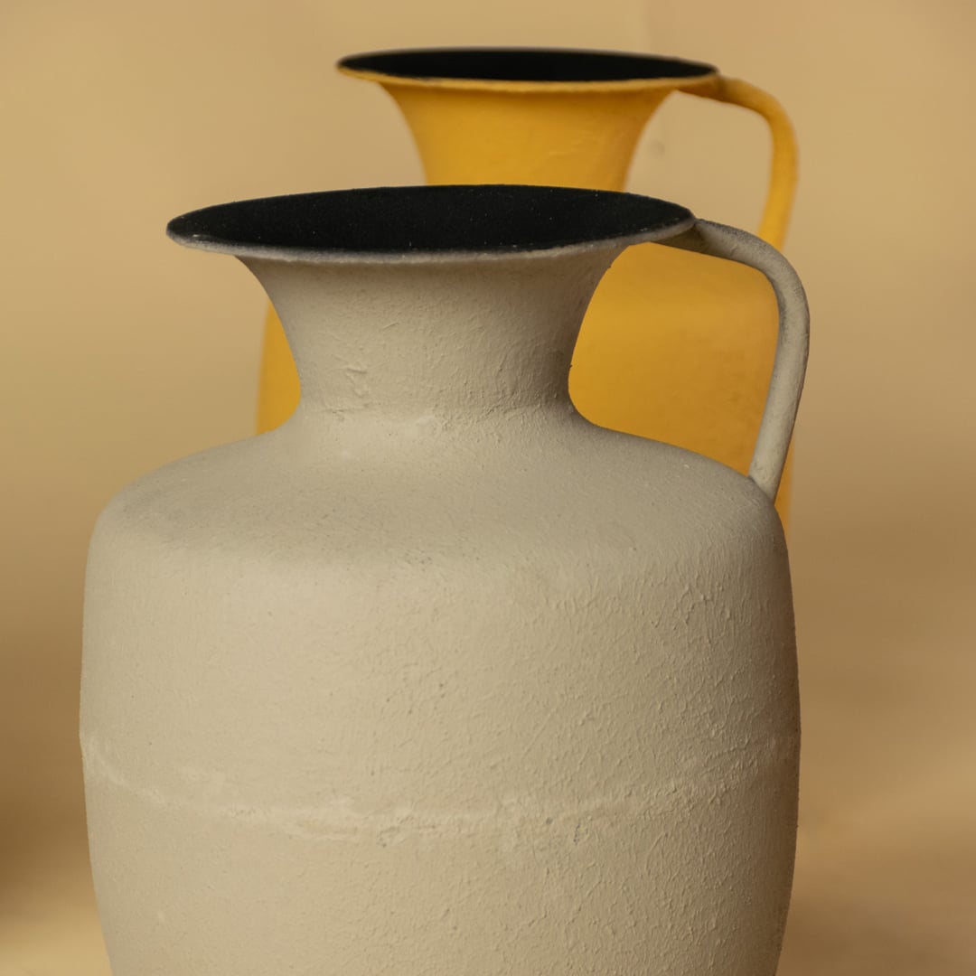 Closeup of yellow metal jug vase showing its textured surface flared top and curved handle perfect for bold stylish home decor.