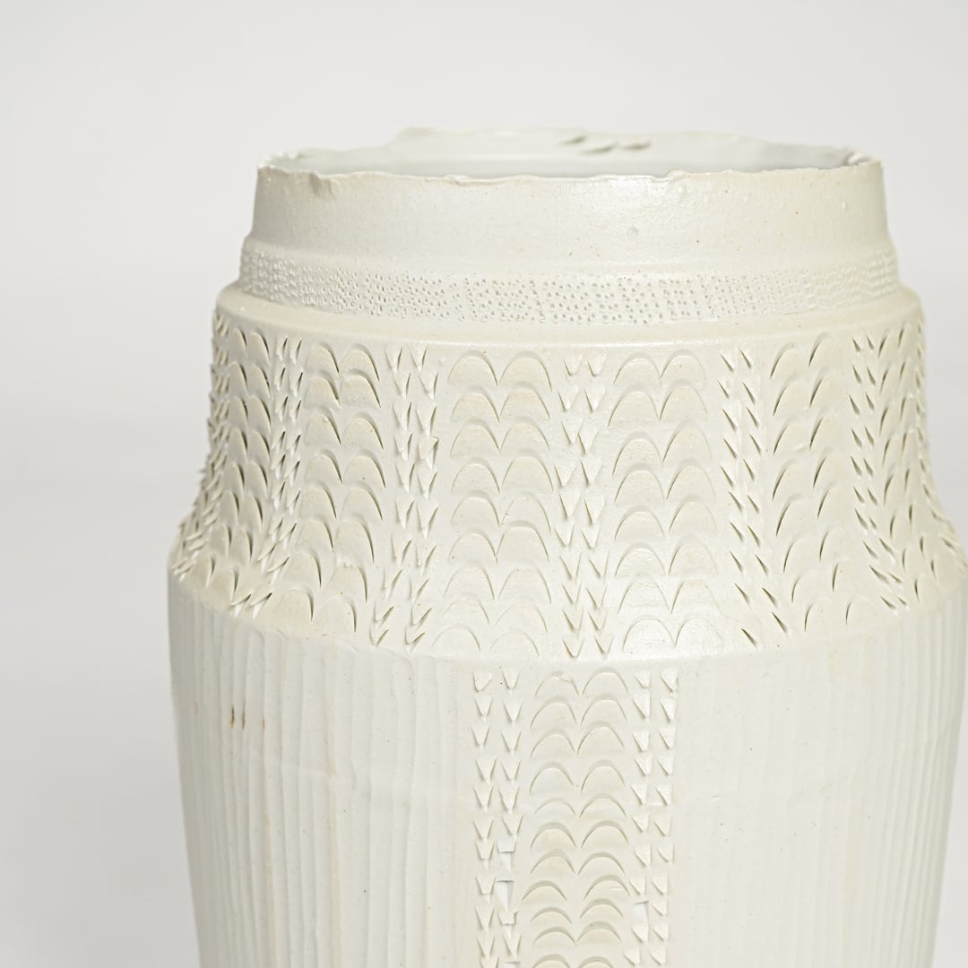 Close view of white ceramic textured vase featuring intricate surface pattern and elegant handcrafted detailing.
