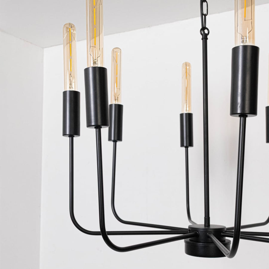 Detailed closeup of exposed vintage Edison tube bulb with black metal cylindrical socket on contemporary chandelier curved arm.