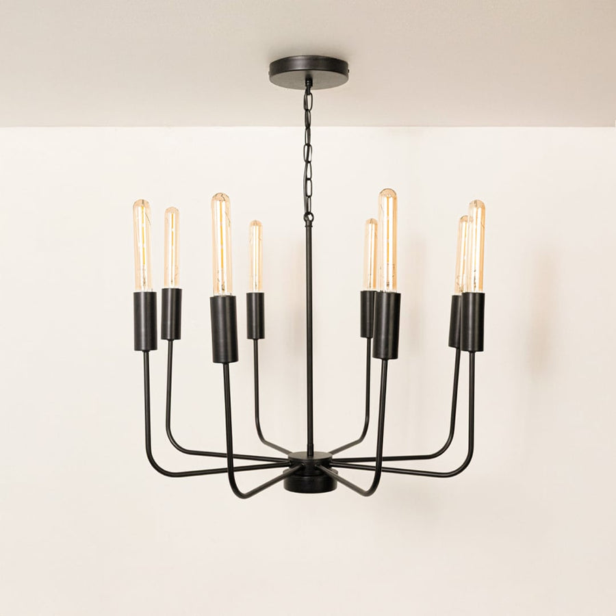 Contemporary black metal eight arm chandelier with chain and Edison tube bulb sockets turned off displayed on white background.