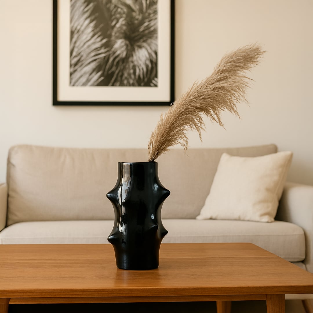 Modern black ceramic vase with artistic sculpted design styled with pampas grass in a cozy living room.