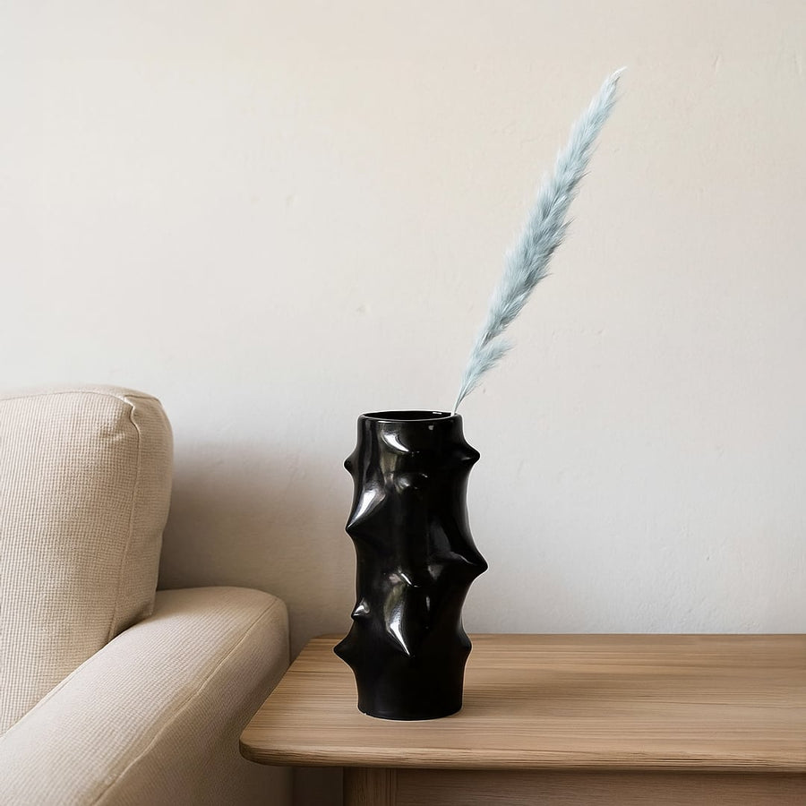 Black sculptural vase with dried stem styled on console table adding bold artistic contrast to modern home Decor.