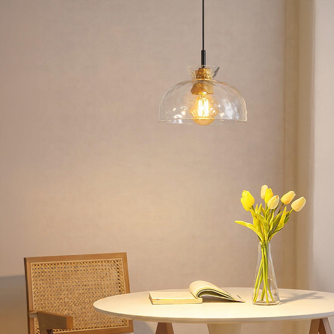 Clear textured glass and brass metal pendant light creating cozy ambience in modern dining interiors.