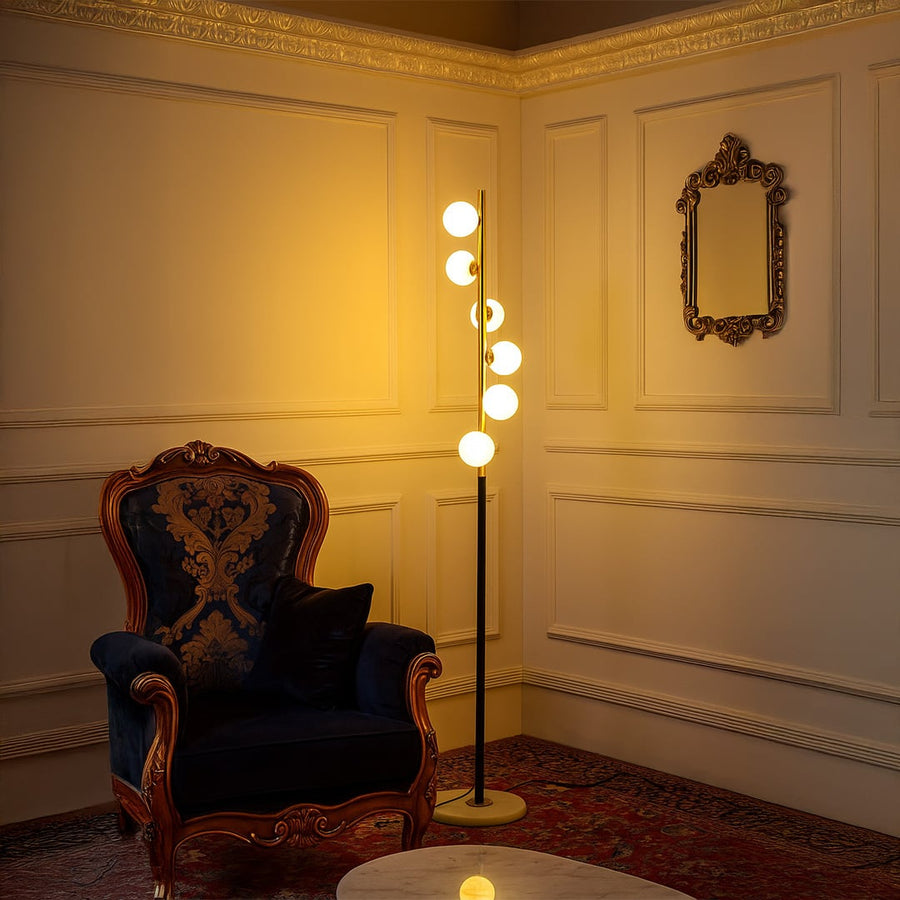Elegant globe floor lamp turned on in a luxurious living room with vintage chair and classic wall paneling.