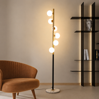 Modern gold floor lamp with globe bulbs placed beside accent chair adding warm contemporary living room lighting.