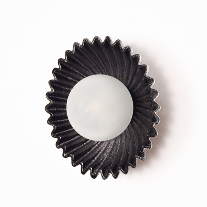 Wall light shown unlit on a white background focusing on the circular shape textured metal finish and clean modern styling.