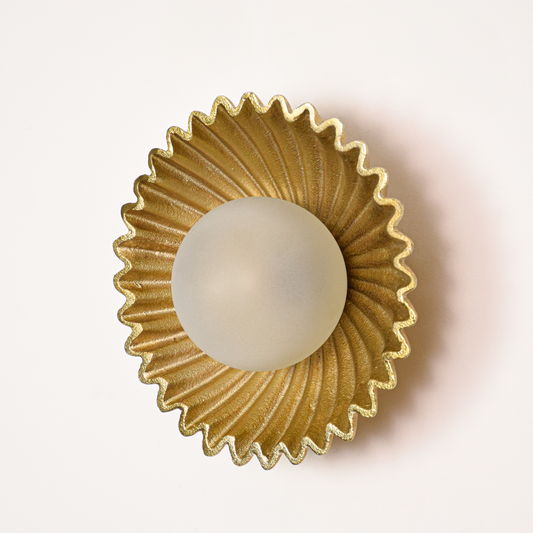 Wall light off on white background featuring gold fluted metal plate with centered glass globe for minimalist product display.