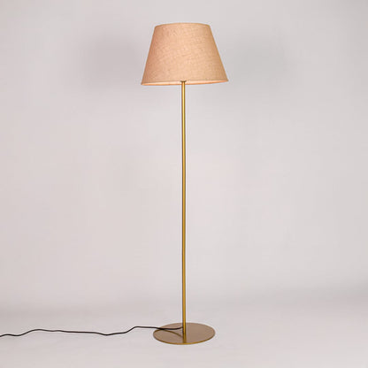Gold metal floor lamp glowing warmly through beige fabric shade on white background for cozy home Decor.