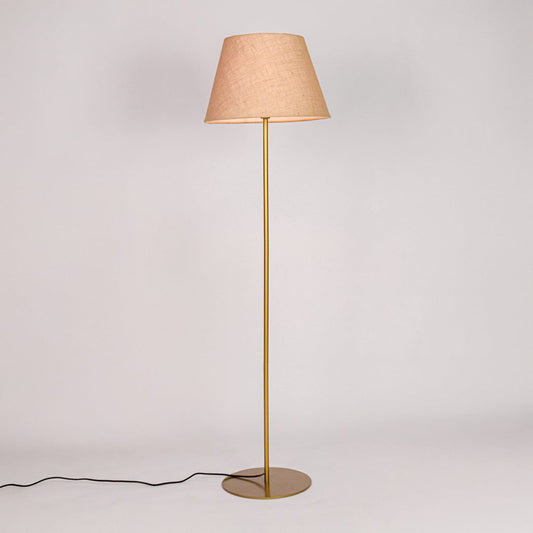 Gold metal floor lamp glowing warmly through beige fabric shade on white background for cozy home Decor.