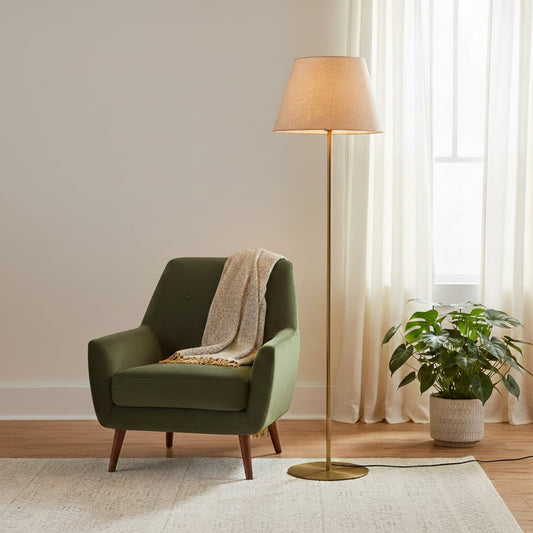 Modern gold metal floor lamp with beige fabric shade placed in living room corner for warm ambient lighting Decor.