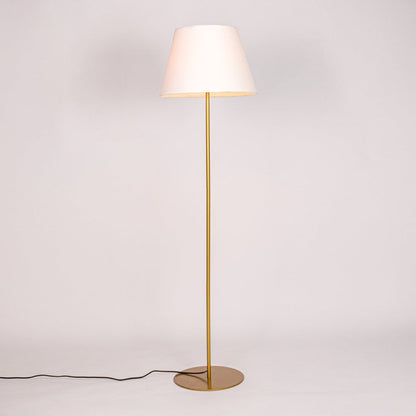 Gold floor lamp illuminated with warm glow through white fabric shade against minimal white studio background.