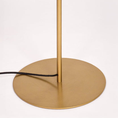 Closeup of round gold metal base with slim sturdy stand highlighting stable contemporary floor lamp for home Decor.