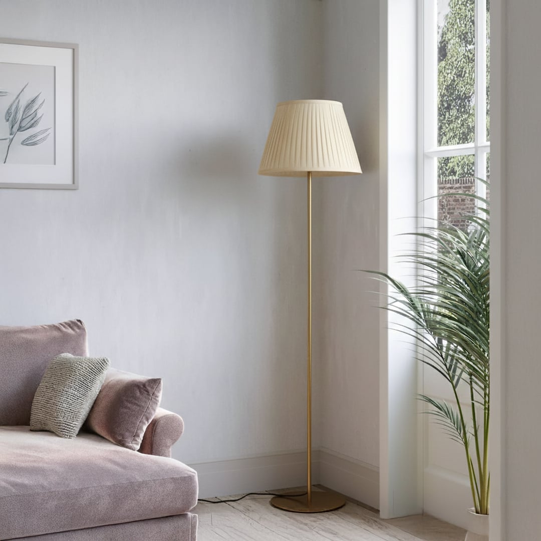 Modern gold metal floor lamp with pleated cream fabric shade placed in living room corner for warm ambient lighting Decor.