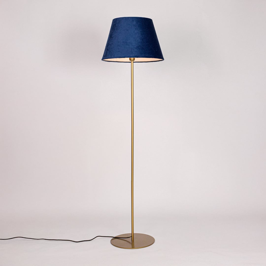 Gold metal floor lamp with blue fabric shade illuminated on white background for soft ambient home lighting Decor.