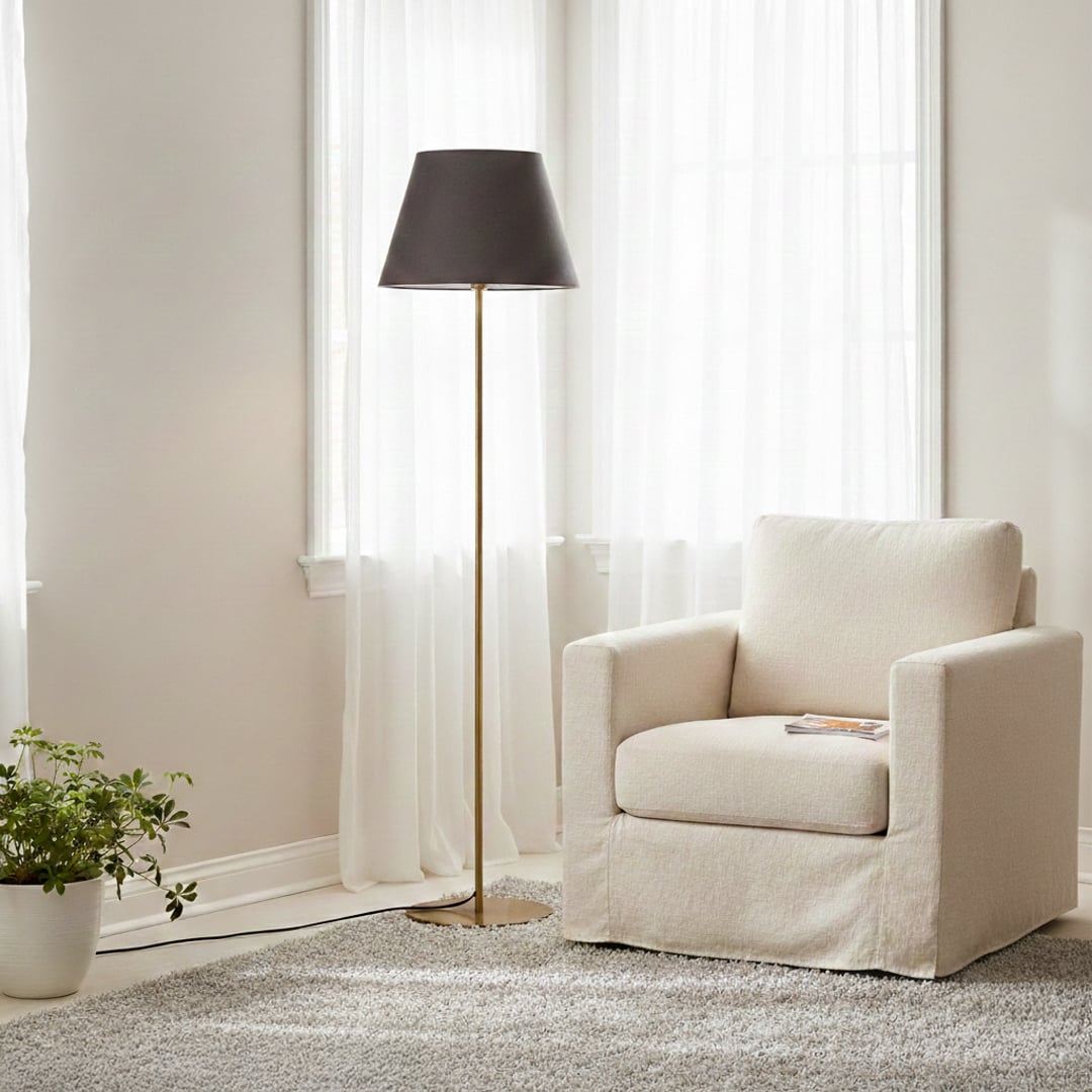 Modern gold metal floor lamp with dark grey fabric shade placed near armchair in elegant living room for soft ambient lighting Decor.