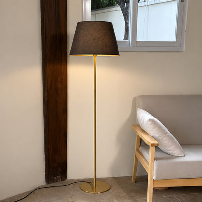Black fabric shade floor lamp with brass finish providing sophisticated ambient lighting for stylish bedroom decor.