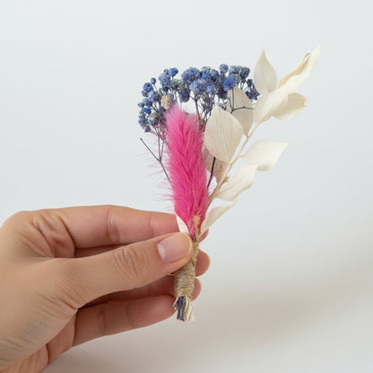 Dried flower bouquet with pink blue and ivory preserved florals held in hand on white background for natural home decor styling.