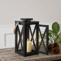 Modern black metal candle lantern with cross frame design adding decorative ambient lighting to outdoor living spaces.