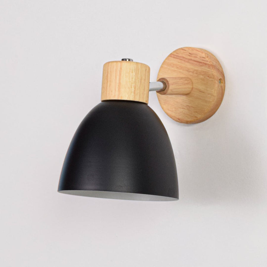 Unlit matte black metal wall sconce with natural wood details isolated on a clean white background showcasing its simple bell shape design.