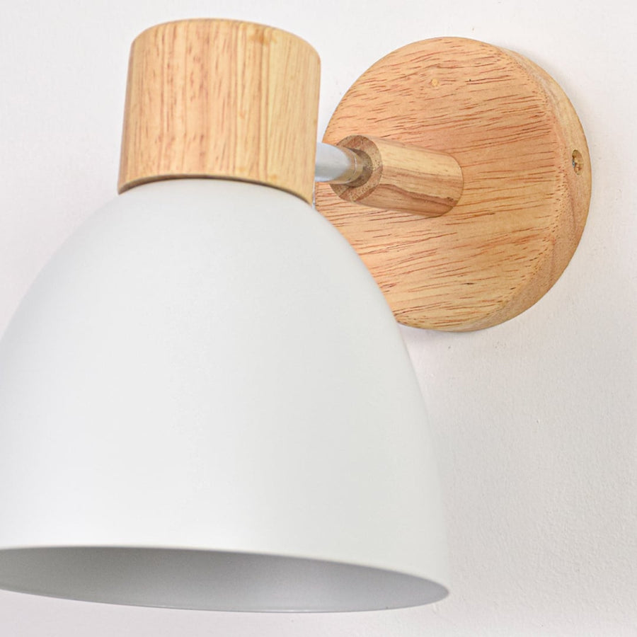 White metal wall lamp closeup showing smooth shade finish and natural wood backplate for soft modern wall lighting decor.