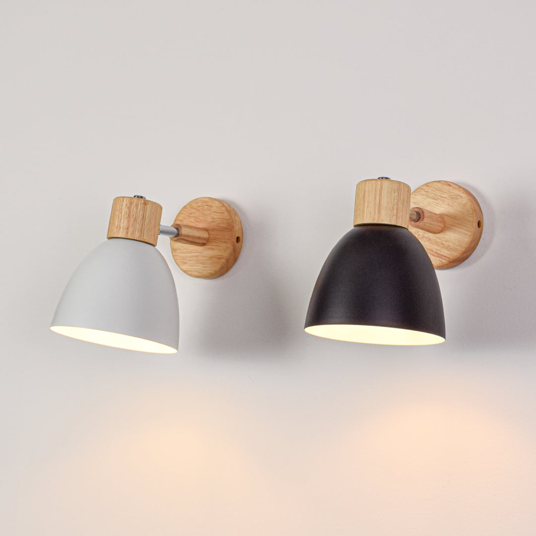 Grouped wall lights with white and black metal shades switched on creating warm balanced lighting for contemporary interior walls.
