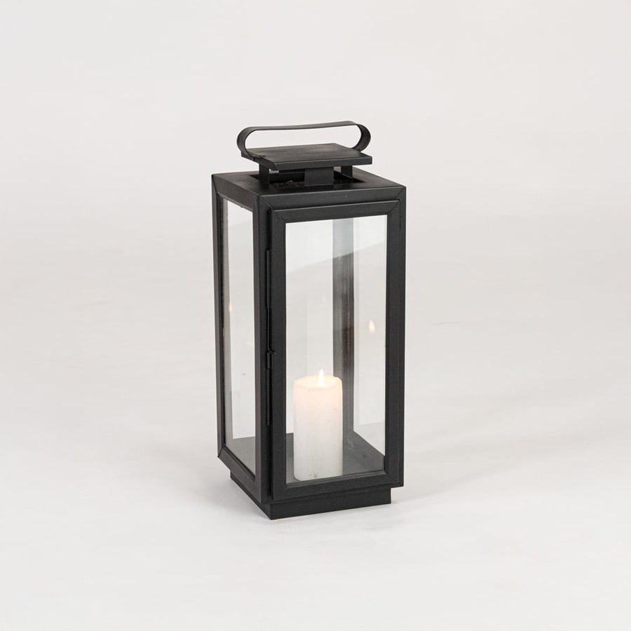 Minimal black metal candle lantern with transparent glass panels on white background perfect for festive home Decor.