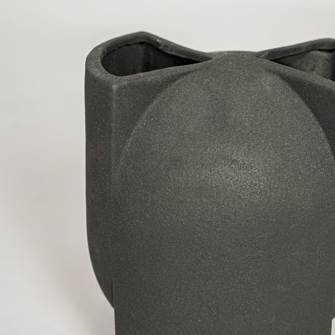 Closeup of matte black ceramic vase with curved abstract form ideal for elegant home decor shelf or side table styling.