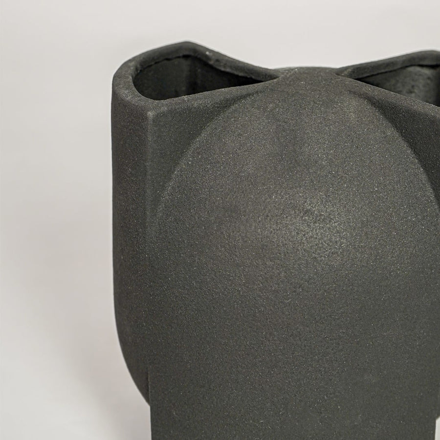 Closeup of matte black ceramic vase with curved abstract form ideal for elegant home decor shelf or side table styling.