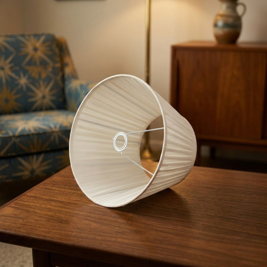 Cream pleated fabric lampshade placed on a wooden table in a cozy living room adding timeless charm and warmth.