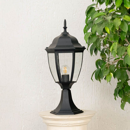 Stylish outdoor black pillar lamp with transparent glass shade placed on stone pillar perfect for villa garden decor.