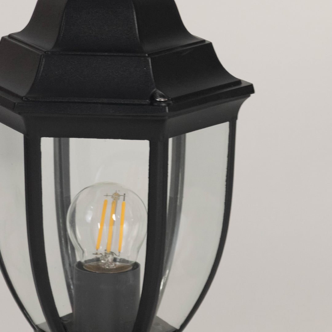 Closeup view of outdoor black pillar lamp showing clear glass design and LED bulb with elegant vintage modern finish.
